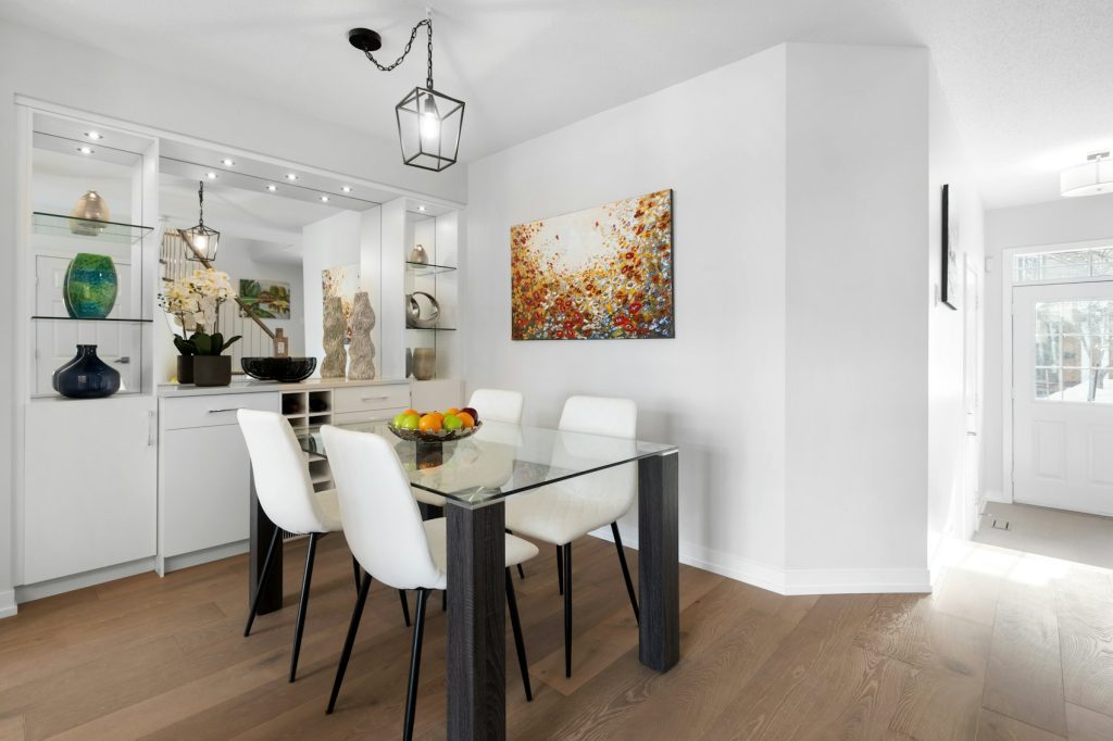 Salle à manger avec table en verre et chaises blanches - photo d'illustration, programmes Confiance Immobilier